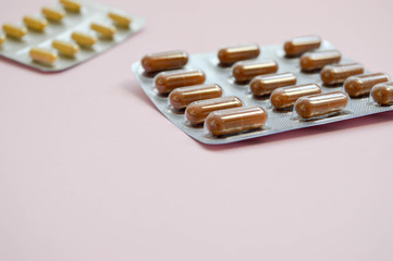 Medical pharmaceutical brown medications for the treatment of diseases and the killing of microbes and viruses tablets and vitamins blisters blisters from coronavirus covid-19 on a pink background