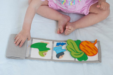 Baby playing with handmade textile book. Child opening an ineractive book with funny felt toys....