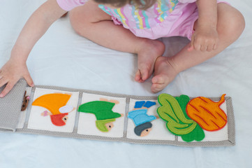 Baby playing with handmade textile book. Child opening an ineractive book with funny felt toys....