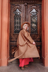 Obraz premium blonde in red dress and hat in the city. Fashion style portrait of blonde model. girl posing at the camera