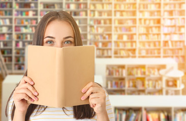 Portrait of beautiful woman with book in modern library