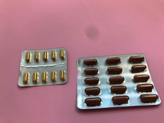 Medical pharmaceutical brown medications for the treatment of diseases and the killing of microbes and viruses tablets and vitamins blisters blisters from coronavirus covid-19 on a pink background