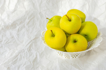 Yellow apples on a plate on a white paper background, still life with apples, Golden Apples