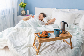 Woman is sleeping in a bedroom with breakfast in front of her