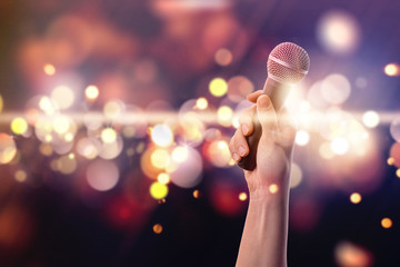 Female hand with microphone against blurred lights