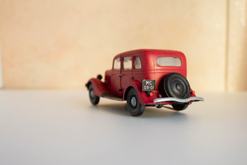 Miniature toy red retro car on a white background. Red plastic hand-built model.