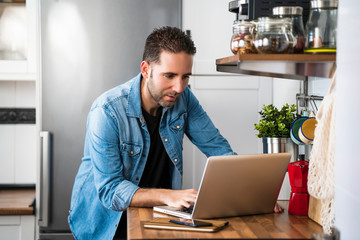 Young man working with laptop in his apartment kitchen. Working at home and stay at home.