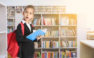 Shocked little schoolgirl in modern library