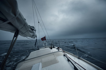 Yacht sailing in a thunderstorm on a rainy autumn day. Top down view from the deck to the bow, mast...