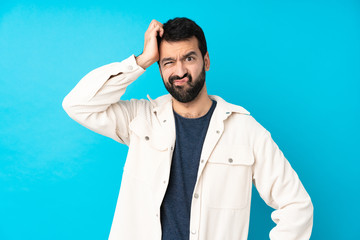 Young handsome man with white corduroy jacket over isolated blue background with an expression of...