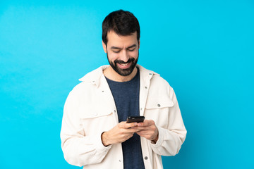 Young handsome man with white corduroy jacket over isolated blue background sending a message with...