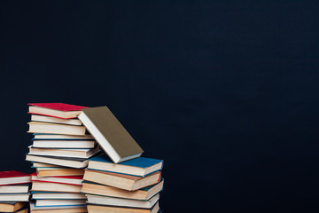 many stacks of educational books in the university library on a black background
