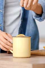 Beautiful young woman making tea with lemon at home, closeup
