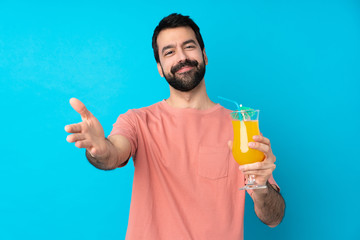 Young man over holding a cocktail over isolated blue background presenting and inviting to come with hand