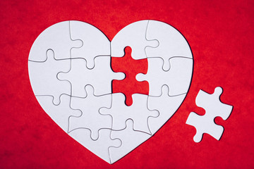 Heart-shaped jigsaw puzzle on color background. Puzzle heart on wooden background. A missing piece of the heart puzzle. Heart shape jigsaw puzzle. Puzzles in the shape of a heart.
