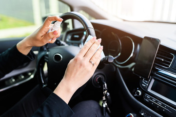 Female hands is disinfecting the steering wheel with an antiseptic to protection from viruses, the face is not visible. Coronavirus pandemia, epidemia covid-19