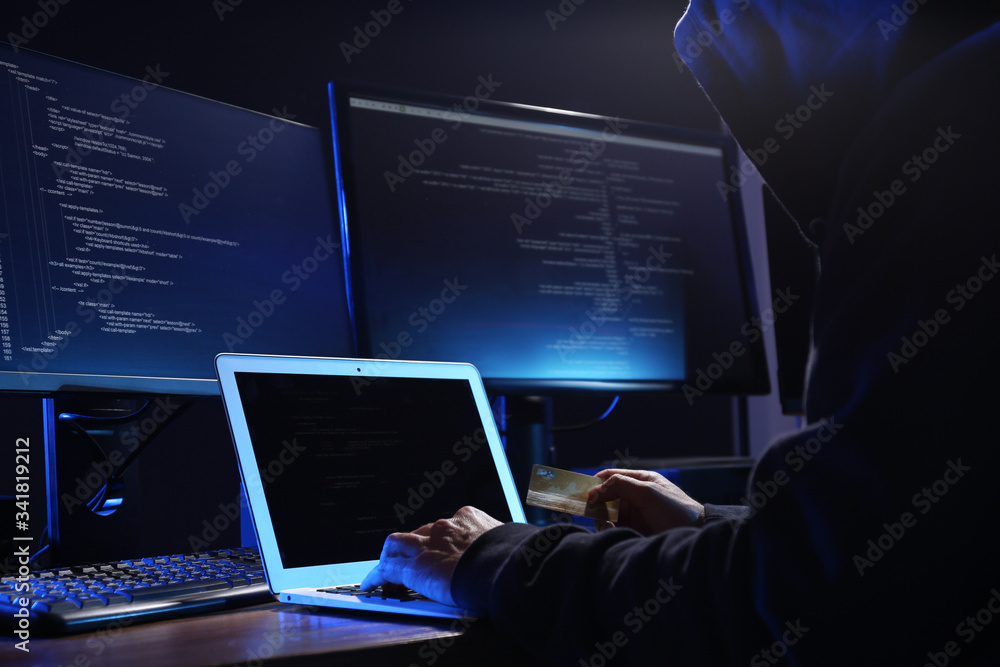 Poster hacker with computers and credit card in dark room, closeup. cyber crime