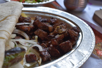 Close up view of liver kebab in a plate served with onions and special bread