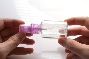 small pink plastic bottle with an antiseptic in hands