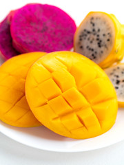 Fresh sweet mango and sliced dragon fruit on white background. Exotic tropical fruits for healthy and vegeterian diet.