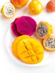 Fresh sweet mango and sliced dragon fruit on white background. Exotic tropical fruits for healthy and vegeterian diet.