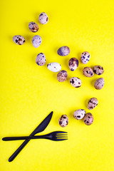 Beautiful yellow background with quail eggs. Food background with knife and fork. Quail eggs.