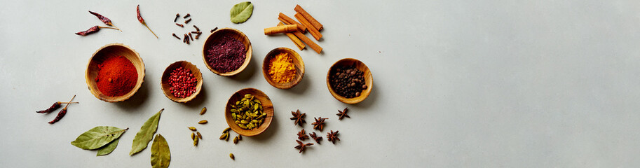 Various colorful spices in wood bowls on concrete background. Top view with copy space. Different Pepper, turmeric, paprika, rosemary, chilly, cardamom, cinnamon, anise, cloves. - obrazy, fototapety, plakaty