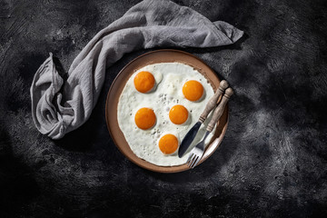 Fried eggs on a ceramic plate with knife and fork