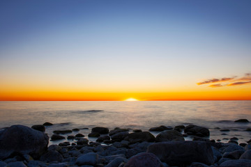 Amazing cloudy spring sunset over deep blue ocean and endless horizon, with boulders in the foreground island of Gotland in the Baltic Sea, Sweden