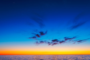 Amazing vibrant spring sunset over deep blue ocean and endless horizon, with small clouds on the colorful sky outside island of Gotland, Sweden