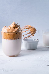 Dalgona coffee with milk and whisk on white background. Korean coffee. Vertical picture.