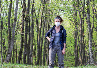 woman wearing medical mask in green forest