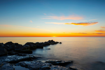 Amazing cloudy spring sunset over deep blue ocean and endless horizon, with boulders in the foreground island of Gotland in the Baltic Sea, Sweden