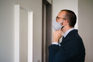 Young businessman getting ready facing mirror and adjusting his protection mask
