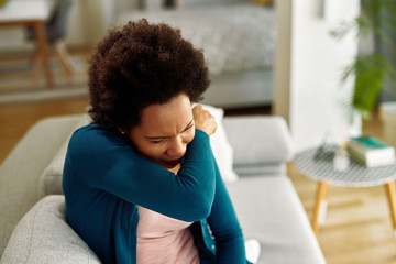 African American woman couching into elbow at home. - Powered by Adobe