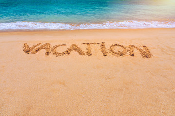 Vacation text on a beach. Vacation written in a sandy tropical beach. 