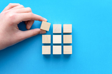 Hand arranging wood blocks in square shape for business strategy, team building or development concept