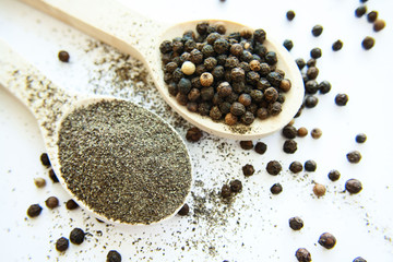 Wooden spoons filled with peppercorns and ground pepper
