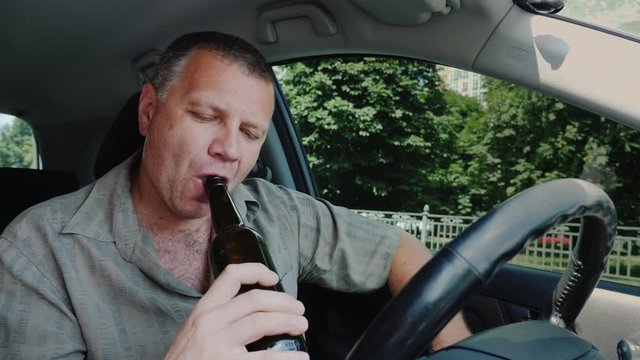 A rude man drinks alcohol in the car. Drunk driving