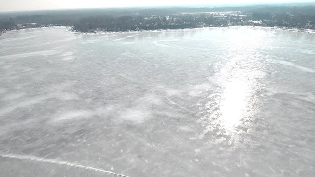 Flying over snow covered houses along frozen icy lakefront, Michigan USA