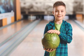 Fototapeta premium Little boy playing bowling in club