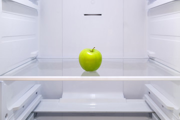 one green Apple on a shelf in an empty refrigerator