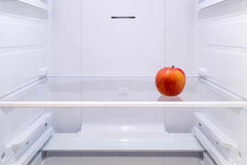 one red Apple on a shelf in an empty refrigerator
