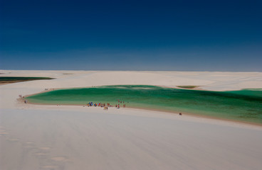 Fototapeta na wymiar Tourists in lagoons surrounded by dunes in the Lençois Maranhenses National Park, Maranhão, Brazil on October 12, 2006. On the north Atlantic coast of Brazil, known for its natural beauty and desert
