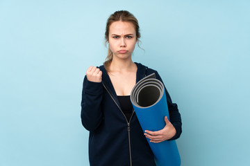 Teenager Russian girl holding mat isolated on blue background with angry gesture