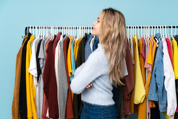 Teenager Russian girl buying some clothes isolated on blue background in lateral position