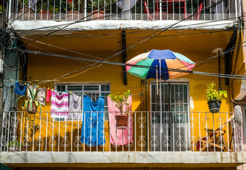 Low angle shot of tropical colored balcony with laundry hanging on clothes line, sun umbrella for shade, city lifestyle. concept, background