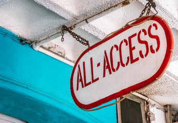 Exterior signage, ALL - ACCESS. Hanging from the ceiling by steel chain. Low angle view, background, copy space