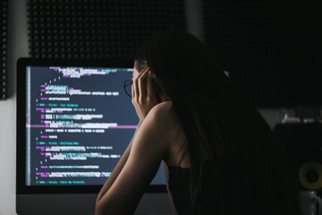 Young female programmer writes program code on a computer. home office