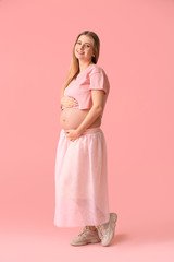 Beautiful young pregnant woman on color background